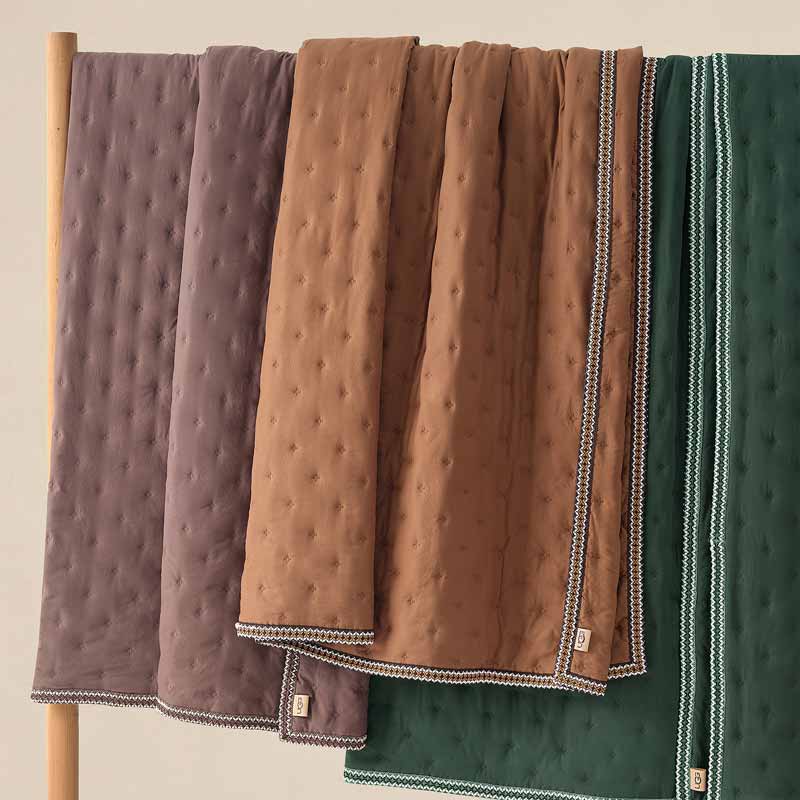 A shot of three new UGG blankets, all in different earth tone colors, draped artistically.